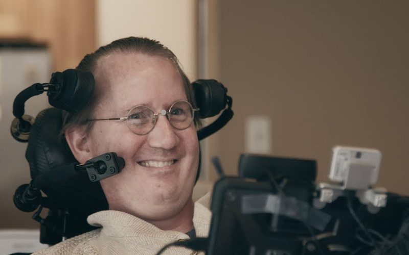 Person smiling while using an assistive communication device